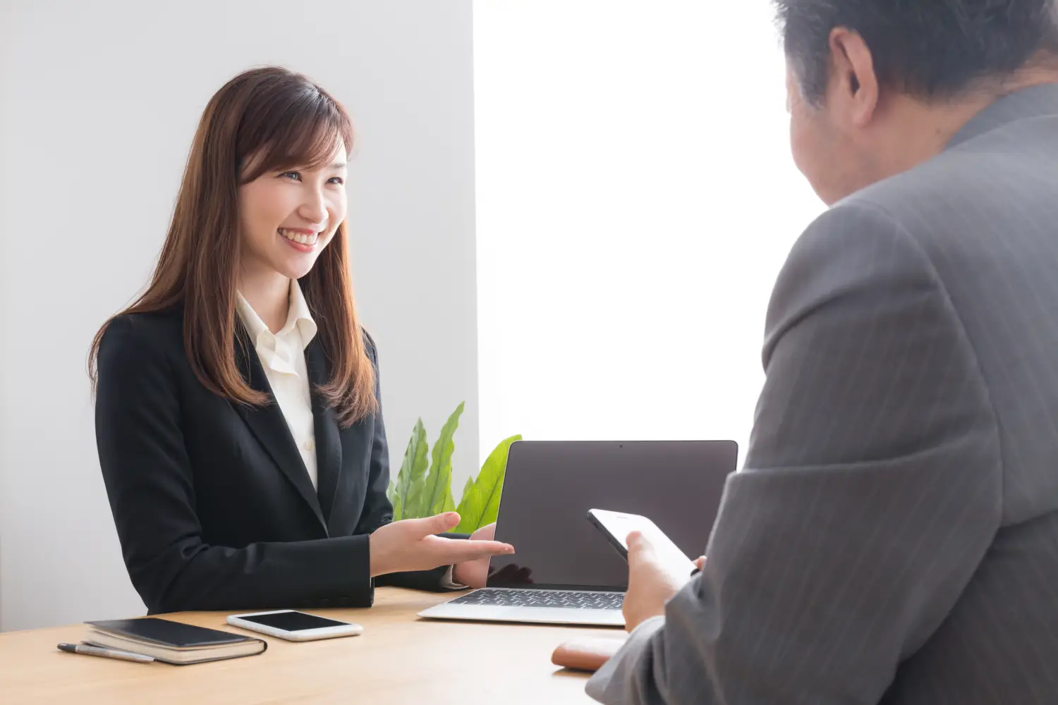 笑顔で説明する女性とPCの写真